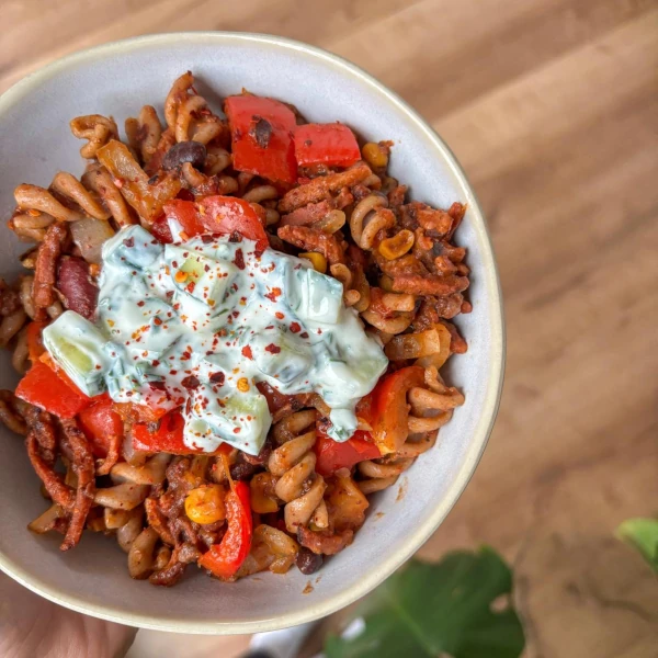 Schüssel mit Spiralnudeln, roten Paprika und Joghurtsauce mit Kräutern